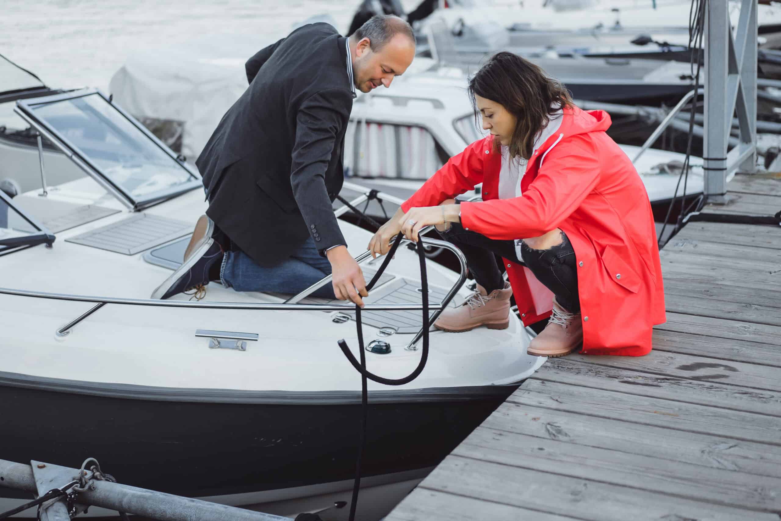 Young couple enjoying a sunny day at a marina surrounded by sailboats.